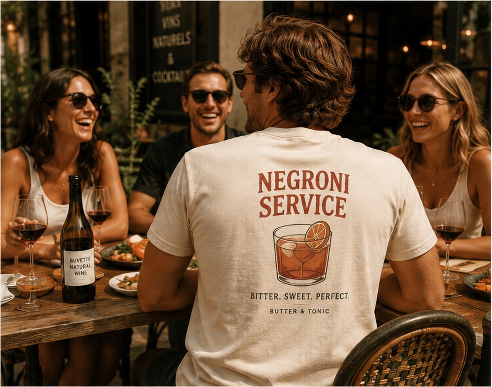Friends sharing food and wine while wearing a Butter & Tonic graphic tee